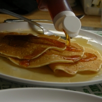 Maple syrup being poured on pancakes at Moore's Pancake House