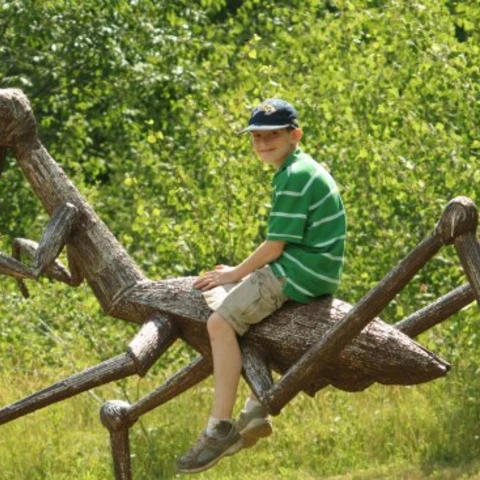 Boy on praying mantis sculpture at Griffis Sculpture Park