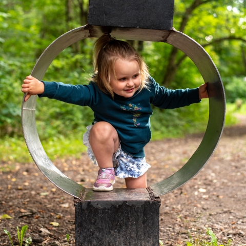 Girl climbing through sculpture at Griffis Sculpture Park
